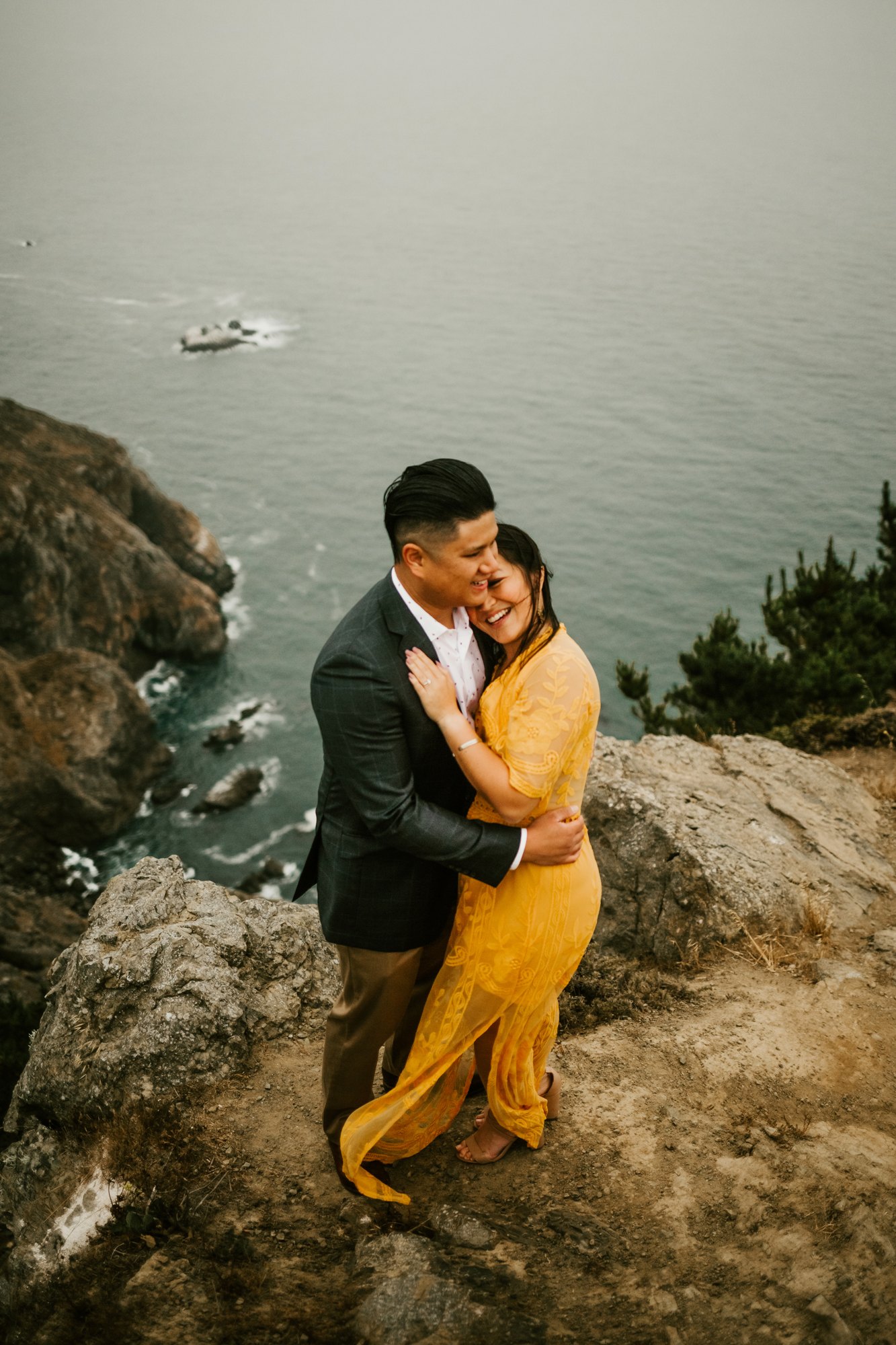 A couple embracing on a cliff above the ocean in Big Sur