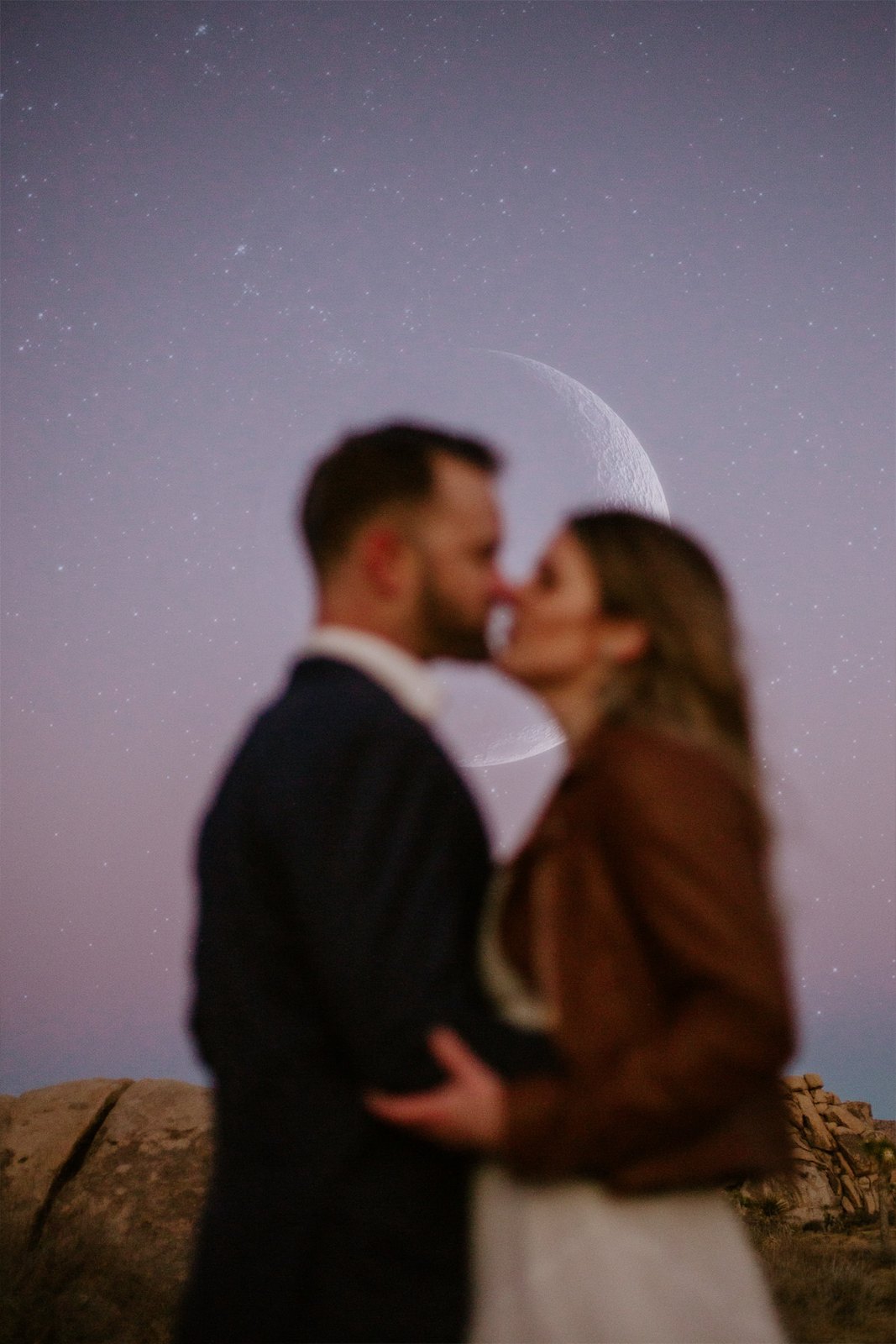A couple kissing under a crescent moon at dusk
