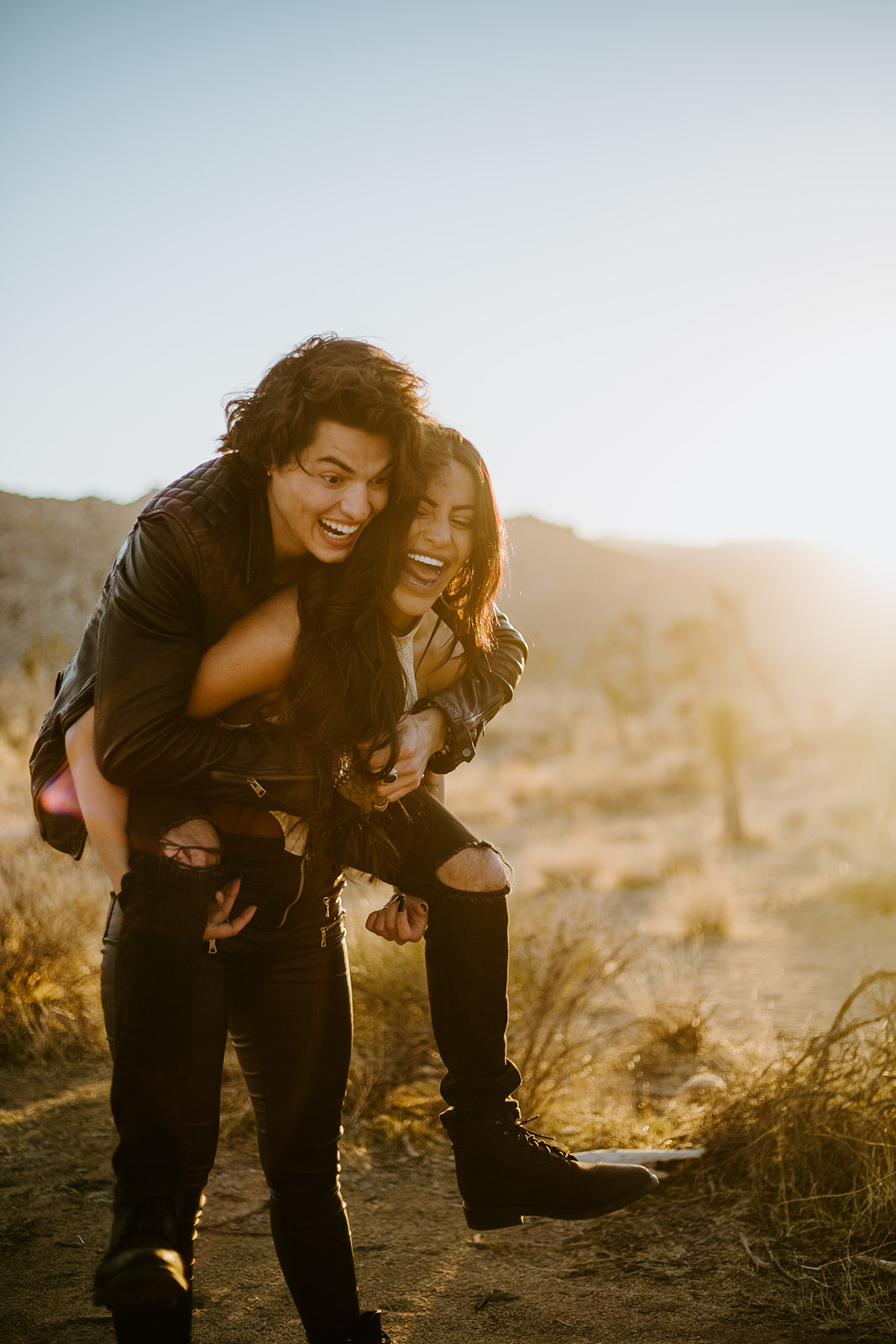 A couple in leather jackets laughing at golden hour in the desert