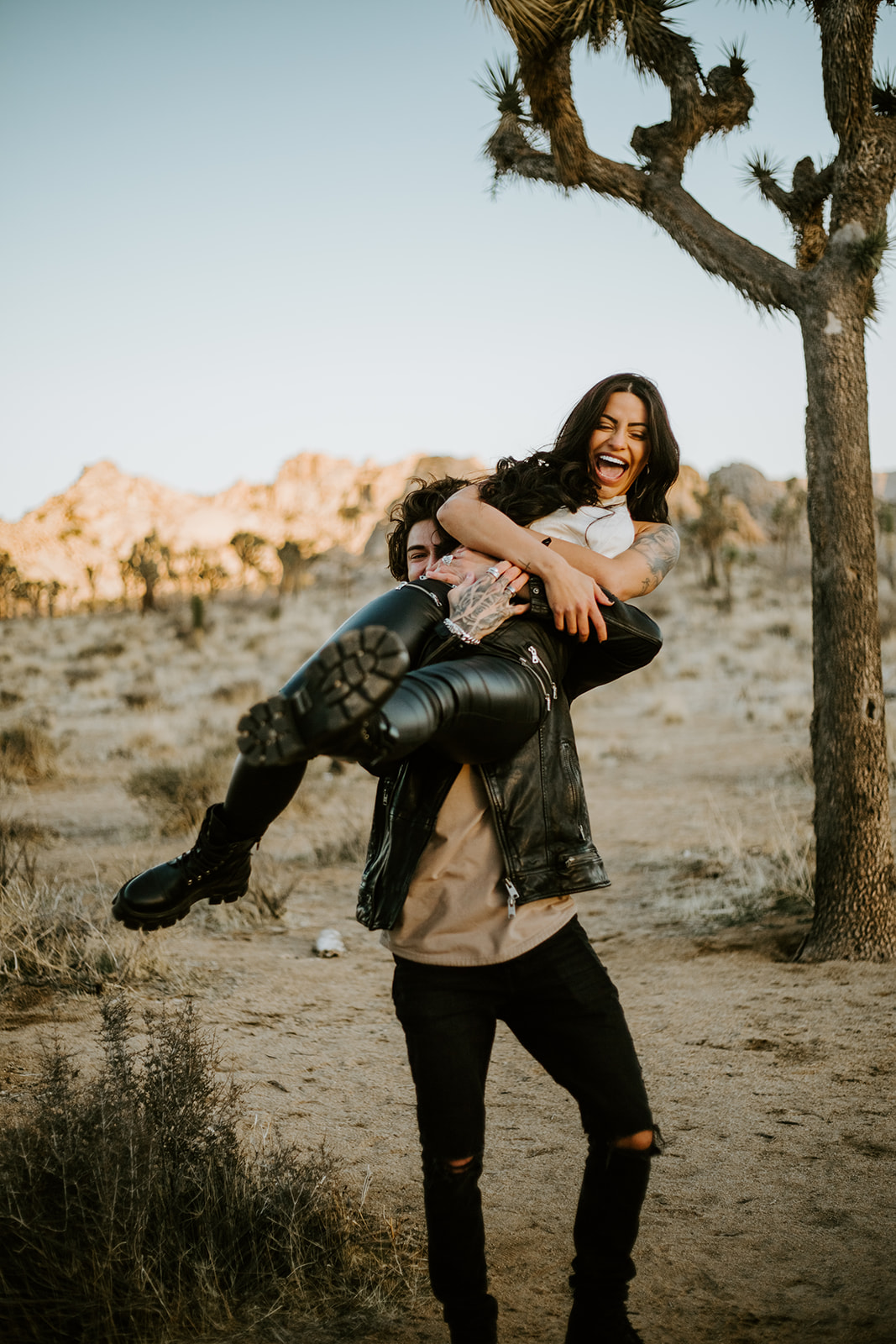 One partner lifting the other under a Joshua tree