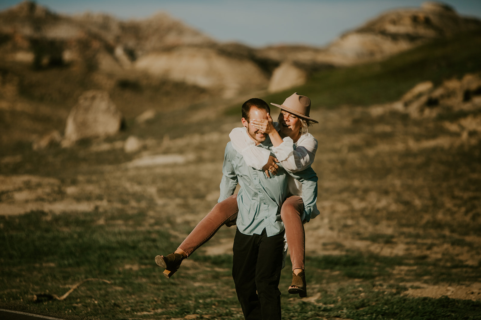 A couple playing in the badlands, one covering the other’s eyes