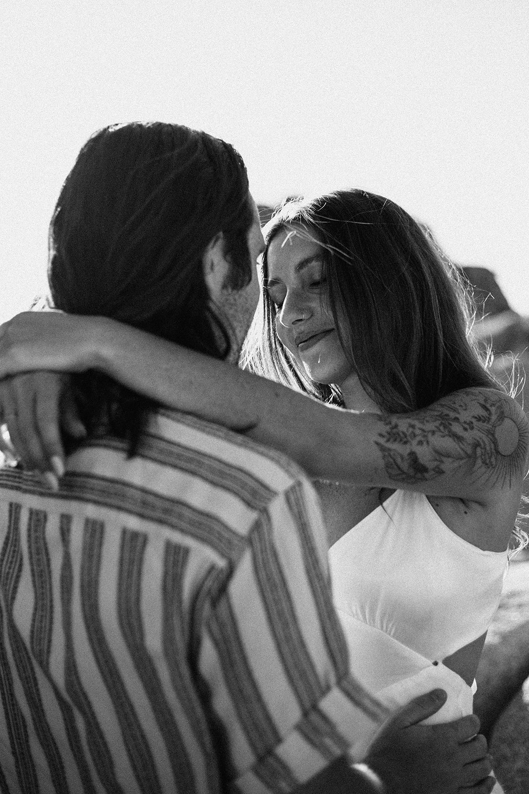 A couple holding each other at golden hour, photographed in black and white